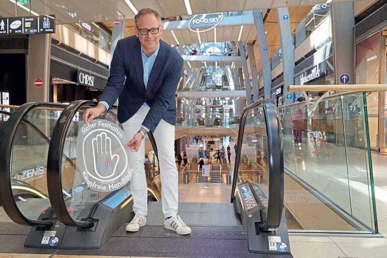 Jörg Harengerd beim Anbringen der Service-Hinweise für sicheres Festhalten an den Rolltreppen-Handläufen